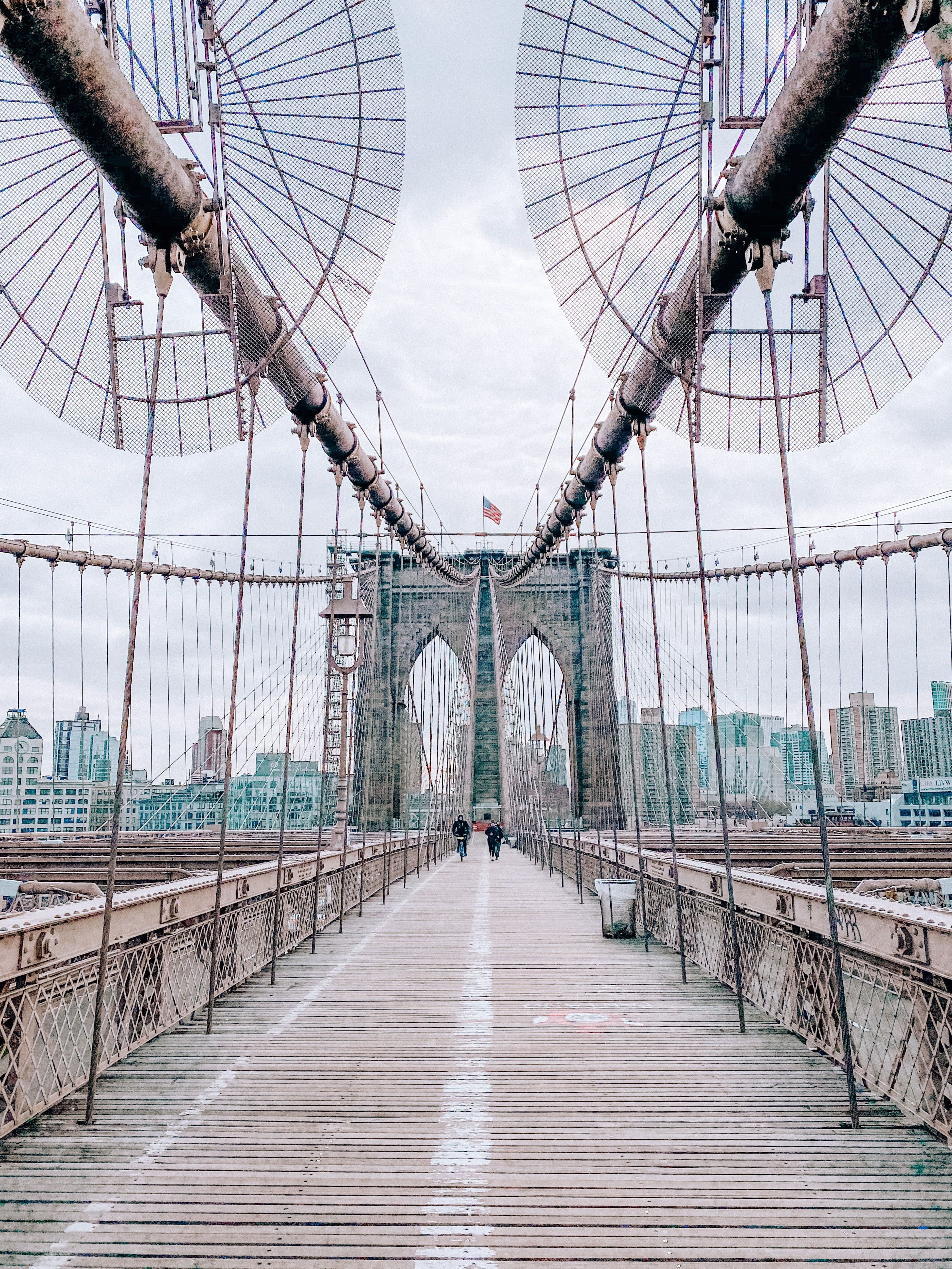 People walking the Brooklyn Bridge promenade toward the Manhattan skyline
